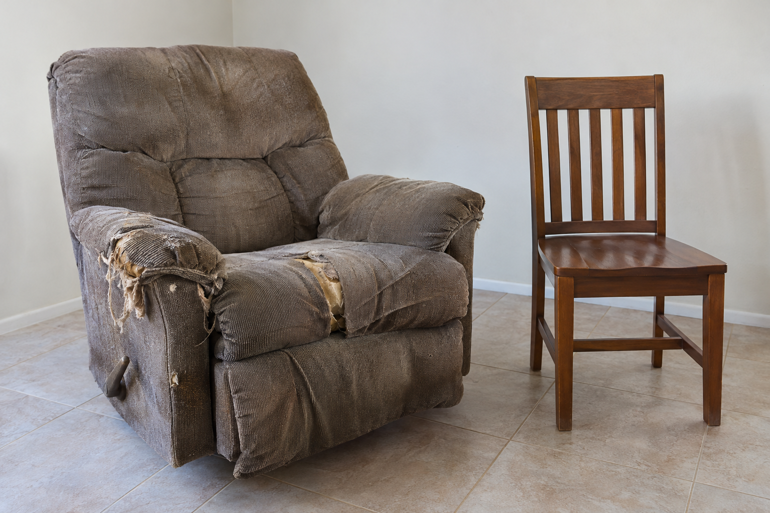 A torn, sagging recliner beside a sound wooden chair